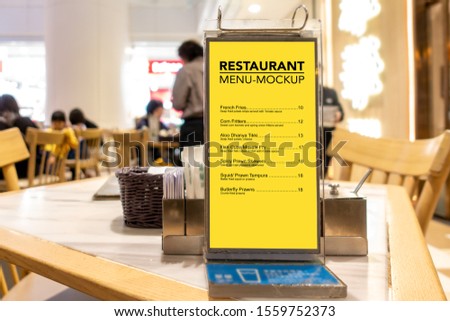 Mock up blank vertical advertising signboard in acrylic frame with clipping path on table in restaurant ,empty space for insert menu list or promotion 