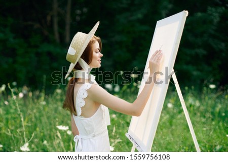 young woman outdoors an easel with white canvas