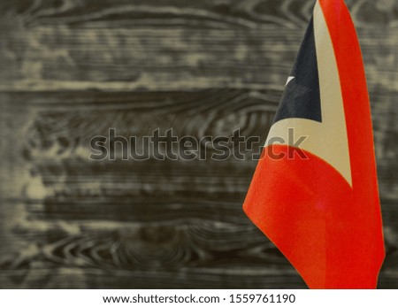 Fragment of the flag of the Republic of East Timor in the foreground blurred wooden background copy space