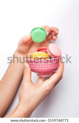Sweet and colourful macaroons or macaron woman's in hand on white background.