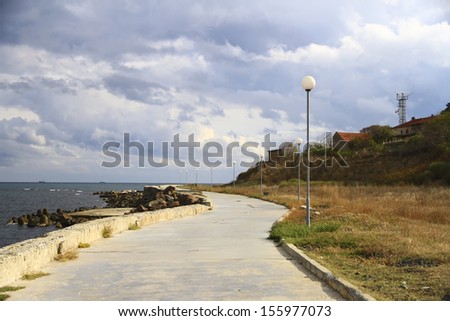 The road along the sea on a background of dark clouds