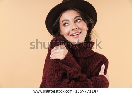 Image of smiling optimistic cute young brunette woman posing isolated over beige wall background.