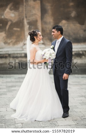 Gorgeous happy couple standing close to each other and looking in eyes at old city background, wedding photo, European city, wedding day in Lviv.
