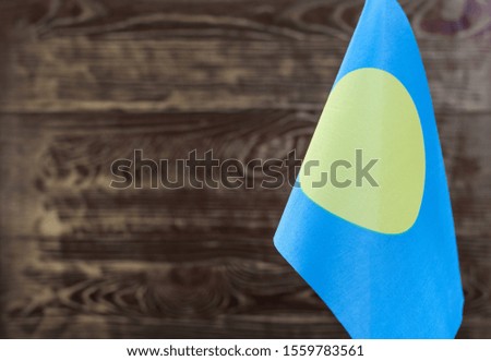 Fragment of the flag of the Republic of Palau in the foreground blurred wooden background copy space