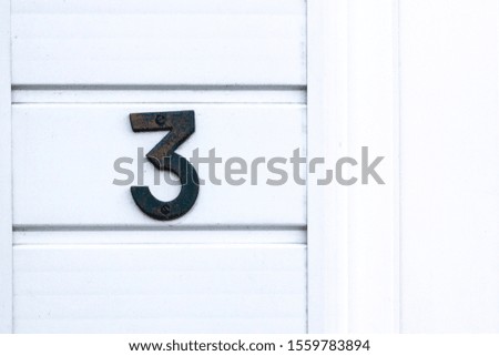 House number 3 on a white wooden wall next to the front door