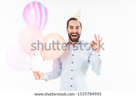 Image of pleased party man holding air balloons and gesturing ok sign isolated over white background