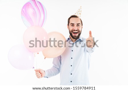 Image of excited party man holding air balloons and gesturing thumb up isolated over white background