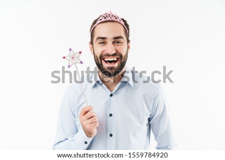 Image of beautiful feminine man wearing princess crown smiling and holding magical wand isolated over white background