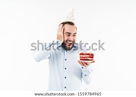 Image of amazed party man smiling and holding birthday cake with candle isolated over white background
