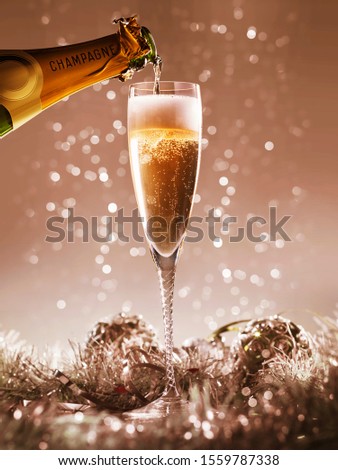pouring champagne into a champagne glass on a bokeh christmas background