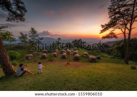 Dad taking pictures of his daughter in sunset viewpoint at Huai Nam Dang National Park, Thailand
