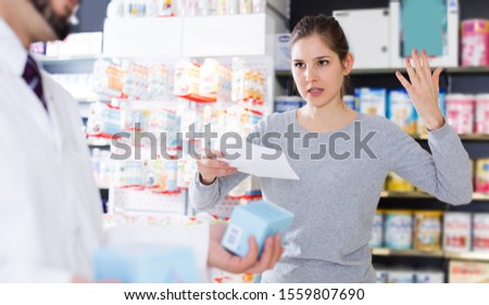 Portrait of unhappy woman client who is dissatisfied of recommended medicines in pharmacy. Royalty-Free Stock Photo #1559807690