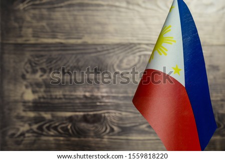 Fragment of the flag of the Republic of the Philippines in the foreground a blurred wooden background copy space