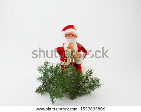 A festive composition of Santa Claus sitting on a chair holding a golden bell in his hand. Next to it are gifts, Christmas tree branches and beautifully packaged gifts. White background front photo