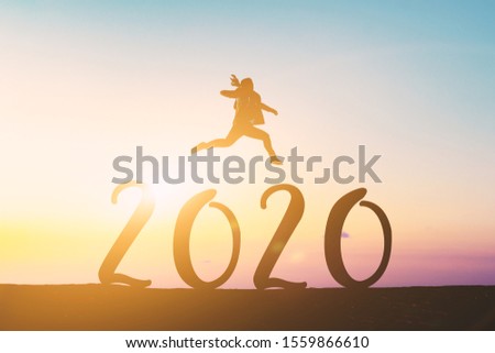 Women jumping to 2020 text. Happy new year concept.