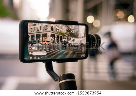 Man using phone with stabilizer and taking pictures and live video in New York city. Vlog, video blogging, street photography concept. 