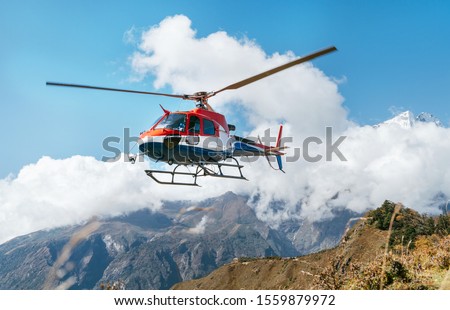 Red and white Medical Rescue helicopter landing in high altitude Himalayas mountains. Safety and travel insurance concept image. Royalty-Free Stock Photo #1559879972