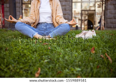 Close up picture of a young female sitting on the grass lawn taking off her shoes
