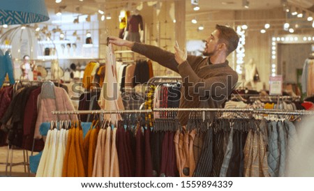 Hansome guy photographs things in a clothing store
