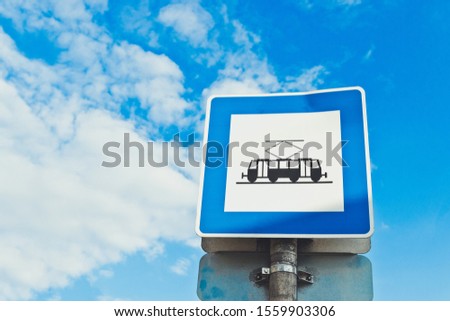 Tram station sign on a street in the city against a blue sky. Traffic sign