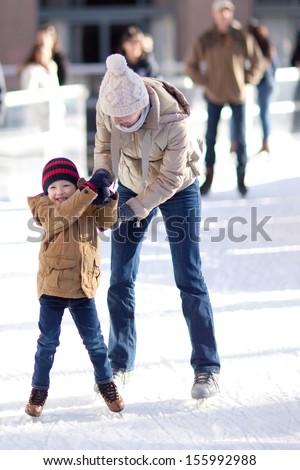 happy excited little boy and his young mother learning ice-skating