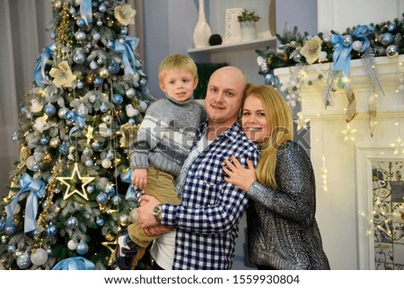 Young parents with their son smiling at the camera while celebrating Christmas at home