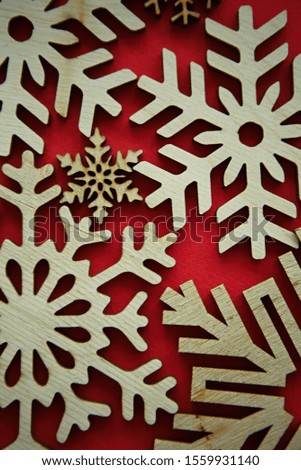 Hand crafted wooden snow flakes on red background.Eco friendly home decor for winter holidays.Decorate house with natural ecological materials for Christmas Eve and Happy New Year celebration party
