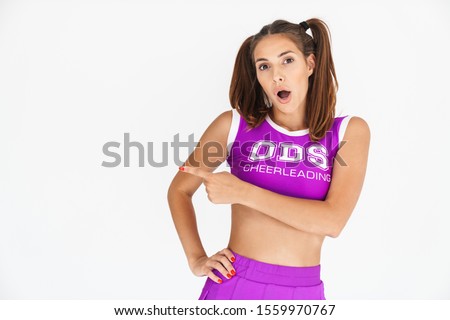 Picture of shocked cheerleader woman isolated over white wall background pointing aside.
