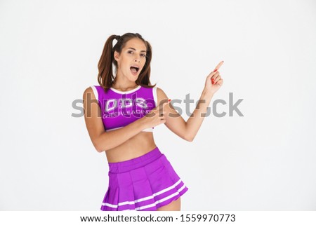 Picture of shocked cheerleader woman isolated over white wall background pointing aside.