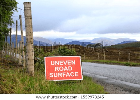 Uneven road surface sign on the road, mountains in background 