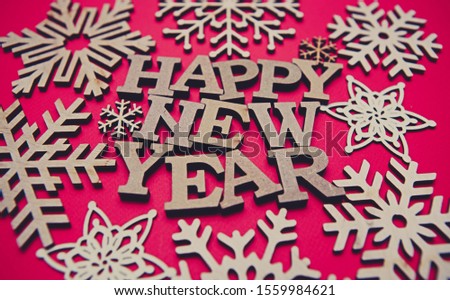 Red Happy New Year background with hand made wooden decor.Handcrafted snowflakes made from eco friendly wood.Decorate home for winter holidays with ecological materials