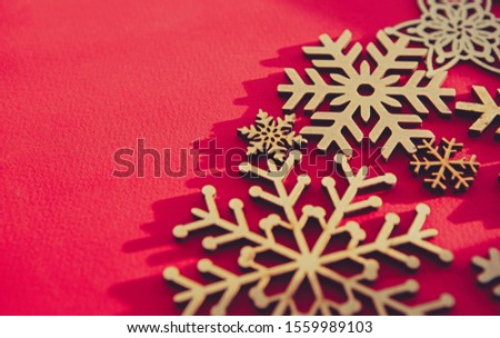 Red Christmas background with handmade wooden snowflakes.Hand crafted and eco friendly home decor for winter holidays.New Year decor in close up for wallpaper