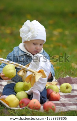 Little girl sits with a basket of apples
