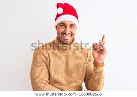 Young handsome man wearing christmas and turtleneck sweater over isolated background with a big smile on face, pointing with hand and finger to the side looking at the camera.