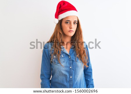 Young beautiful redhead woman wearing christmas hat over isolated background looking sleepy and tired, exhausted for fatigue and hangover, lazy eyes in the morning.