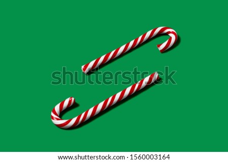 Candy cane striped in Christmas colors on green background. Red and white striped hard candy cane. 