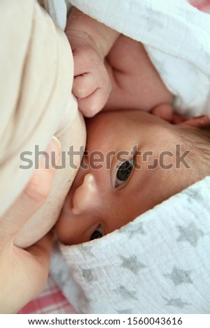 baby wrapped up in blanket looking with big blue eyes just been cared for after having a good sleep in bed with mother stock photograph stock photo