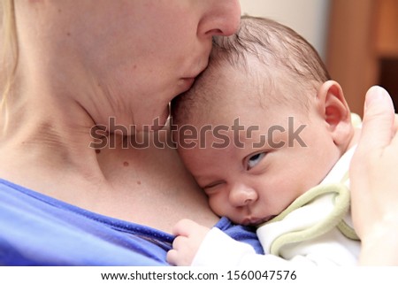 baby wrapped up in blanket with mother looking and just been cared for after having a good sleep in bed at home stock photograph stock photo