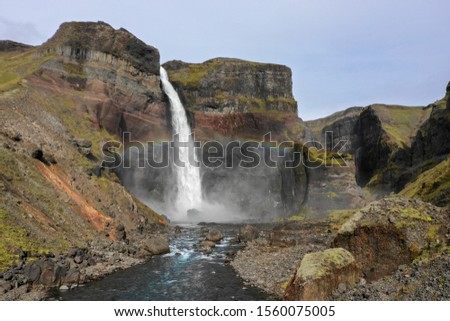 Looking up river towards Haifoss waterfall in Iceland with colorful rainbow Royalty-Free Stock Photo #1560075005