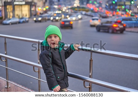portrait of a boy in a jacket and hat on the background of the evening city