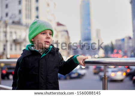 portrait of a boy in a jacket and hat on the background of the evening city