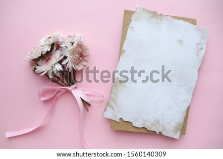 a small bouquet of pink flowers on a white background and an envelope. flat lay. view from above