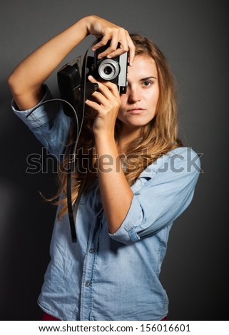 Young photographer woman in jeans jacket holding old camera