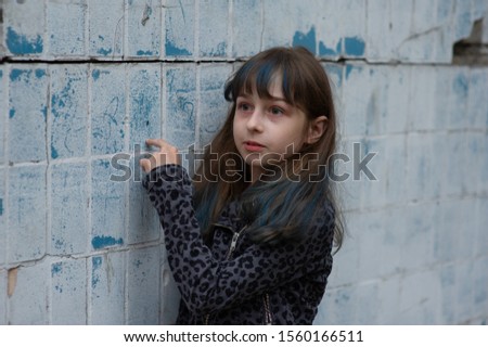 Portrait of nine year old girl. The child is walking in the fresh air. Teenager with blue strands on her hair. The girl with brown hair. A series of photos of a girl of 8 or 9 years old