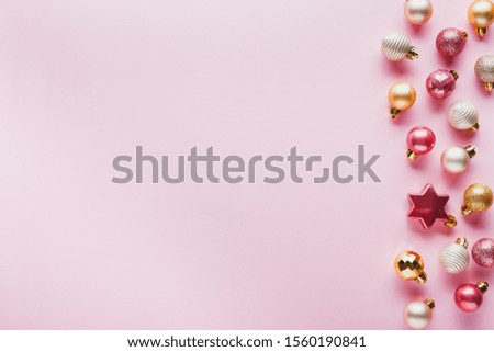 A border of pink and gold small Christmas balls on a pink background
