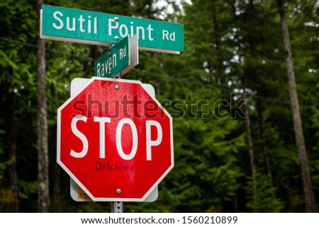 Street sign and stop sign with graffiti on Cortes Island, British Columbia