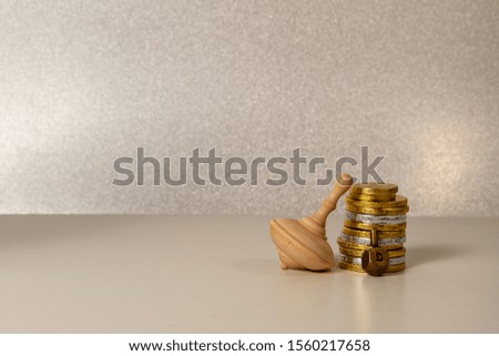 concept of of jewish religion holiday hanukkah with wooden and brass spinning top toys (dreidels) and chocolate coins over wooden table and bright background