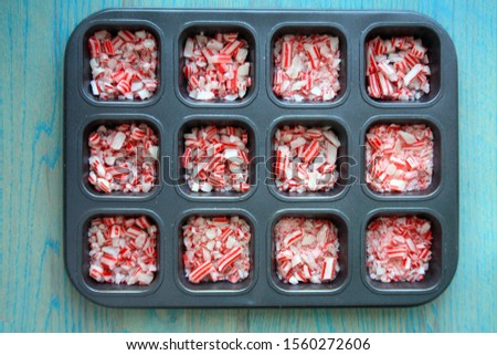 Peppermint candies crushed inside a tray top view. The metal tray has 12 squares inside. All on a rustic green wooden background. 