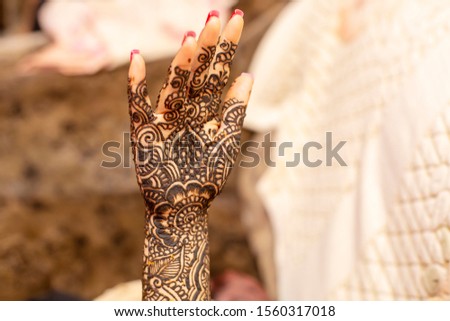 Beautiful henna or mehendi decoration on a hindu bride's hand with redish background with copy space.