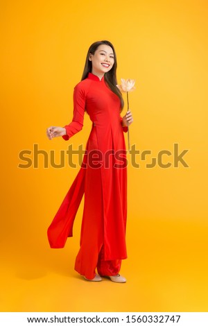 Portrait of a Vietnamese girl with a red dress. In the lotus hand Royalty-Free Stock Photo #1560332747